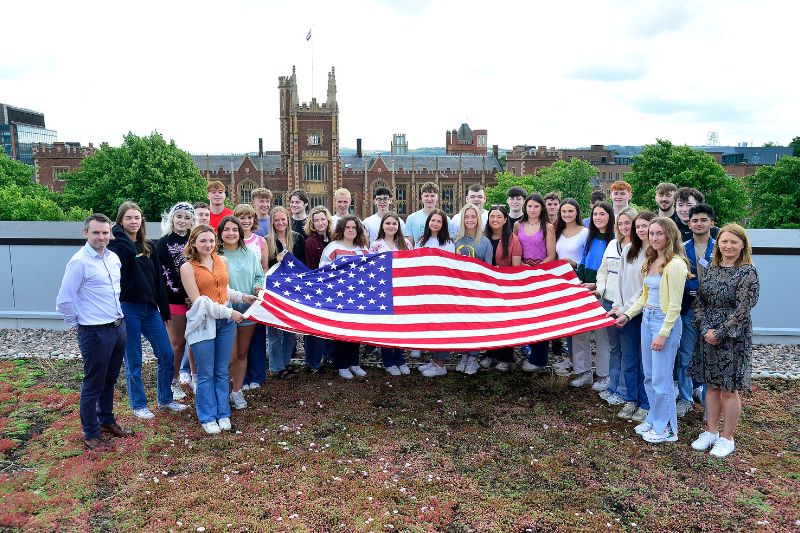 students standing holding American flag at Queen's University roof terrace